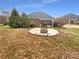 Brick home featuring a stone fire pit sitting on a concrete patio in a spacious backyard at 2702 Occaneechi Ct, Waxhaw, NC 28173