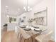 Bright dining room featuring modern chandelier, glass table, and views to kitchen at 4811 Victoria Ave, Charlotte, NC 28269