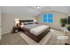 Staged main bedroom featuring a large bed, side tables, and a window with ample light at 5002 Fine Robe Dr, Indian Trail, NC 28079