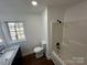 This bathroom has dark wood flooring, a modern vanity, shower-tub combo, and a window at 502 E Maine Ave, Bessemer City, NC 28016