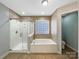 Elegant bathroom featuring a separate glass shower and a soaking tub surrounded by decorative tiling at 621 Ravenglass Dr, Fort Mill, SC 29715