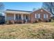 Charming brick and siding home with a cozy front porch, solar panels, and well-manicured landscaping at 9026 Longview Dr, Charlotte, NC 28214