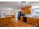 Spacious kitchen with hardwood floors, wood cabinets, black appliances, and a breakfast bar at 9026 Longview Dr, Charlotte, NC 28214
