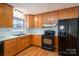 Functional kitchen with wood cabinets, black appliances, and a window view at 9026 Longview Dr, Charlotte, NC 28214