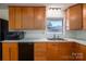 Well-lit kitchen featuring wood cabinets, a stainless steel sink, and black appliances at 9026 Longview Dr, Charlotte, NC 28214