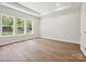 Bright bedroom featuring hardwood floors, tray ceilings, and large windows offering outdoor views at 13134 Macon Hall Dr, Mint Hill, NC 28227