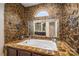 Unique bathroom with stone walls, a large soaking tub, and a window providing natural light at 1974 Glen Manor Ct, Lincolnton, NC 28092