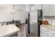 Modern kitchen flows into dining area featuring stainless steel refrigerator, white cabinetry and view to other living spaces at 3428 Braewick Pl, Charlotte, NC 28227