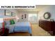 This is a staged bedroom featuring an orange bed frame, tan carpet, a dresser, and art on the walls at 126 Woodhall Way, Troutman, NC 28166