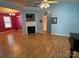 A living room with wood laminate flooring, a fireplace, light blue walls, and a pink accent wall at 1660 Ashridge Rd, Rock Hill, SC 29730