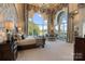 Opulent main bedroom boasts a seating area, water views, and large arched windows with decorative curtains at 18201 Town Harbour Rd, Cornelius, NC 28031