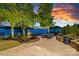 Waterfront patio featuring stone pavers, comfortable seating, mature trees, and lovely sunset views at 18201 Town Harbour Rd, Cornelius, NC 28031