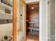 Tranquil cedar sauna with wood benches and flooring, next to glass enclosed shower and shelving at 18201 Town Harbour Rd, Cornelius, NC 28031