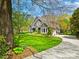 Inviting home showcasing a beautifully landscaped front yard with mature trees and curved driveway at 19000 Hodestone Mews Ct, Davidson, NC 28036