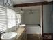 Bright bathroom with dual sinks, jacuzzi tub, decorative fixtures and a door to another room at 201 W Rice St, Landis, NC 28088