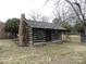 Charming log cabin with stone chimney, wooden shingles and stone trim around the foundation at 201 W Rice St, Landis, NC 28088