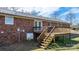 Backyard view of brick home with metal roof and wooden deck with stairs at 2028 Hendil St, Conover, NC 28613