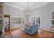 Cozy living room featuring a lake view from the bay window, hardwood flooring, and a stylish chandelier at 213 Patternote Rd, Mooresville, NC 28117
