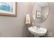Elegant half bathroom with a pedestal sink, round mirror, and stylish wall decor at 2511 Brackley Nw Pl # 1013, Concord, NC 28027