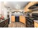Open-concept kitchen with wood cabinets, black appliances, and seamless flow to the living area at 2511 Brackley Nw Pl # 1013, Concord, NC 28027
