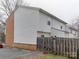 Exterior view of a multi-level townhome with white siding and brick foundation and a wooden fence at 307 French St, Charlotte, NC 28216