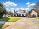 Wide shot of a traditional home with a long driveway and well-kept lawn, under a bright blue sky at 4540 Hounds Run Dr, Matthews, NC 28105