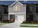New construction townhome featuring light gray siding, a white garage door, and colorful landscaping at 5009 Kellaher Pl, Charlotte, NC 28216
