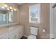 Well-lit bathroom with a neutral color scheme, featuring a vanity with ample storage and a framed mirror above sink at 5153 Glenwood St, Sherrills Ford, NC 28673