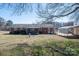 Expansive backyard featuring covered patio, porch swing, metal storage, and red brick house at 605 Castlewood Dr, Gastonia, NC 28056