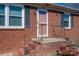 Close-up of the brick home's entrance featuring a salmon colored door with black iron handrails at 605 Castlewood Dr, Gastonia, NC 28056