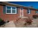 Home entrance with a brick facade, black shutters, salmon colored door and black iron handrails at 605 Castlewood Dr, Gastonia, NC 28056