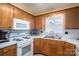 A bright kitchen is displayed with wood cabinets and white appliances and a double-basin sink at 605 Castlewood Dr, Gastonia, NC 28056