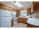 Charming kitchen featuring wood cabinets, white appliances, and a bright window over the sink at 605 Castlewood Dr, Gastonia, NC 28056