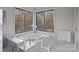 Bright bathroom with a large soaking tub and large windows looking out to nature at 9334 Hunting Ct, Matthews, NC 28105