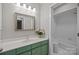 Bathroom features a vanity with green cabinets and a white-tiled shower/tub at 9334 Hunting Ct, Matthews, NC 28105
