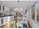 Open-concept dining area with a modern chandelier, glass-topped table, and view into the adjacent living space at 9334 Hunting Ct, Matthews, NC 28105