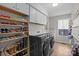 Bright laundry room with gray washer and dryer, lots of shoe storage, white cabinets and light floors at 9334 Hunting Ct, Matthews, NC 28105