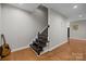 A lower-level stairway with dark wood steps and guitar leaning against the wall at 9334 Hunting Ct, Matthews, NC 28105