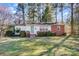 Charming single-story home with a brick and white facade, surrounded by lush greenery and mature trees at 1001 E 8Th Ave, Gastonia, NC 28054