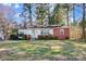 Charming single-story home with a brick and white facade, surrounded by lush greenery and mature trees at 1001 E 8Th Ave, Gastonia, NC 28054