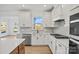 Close-up of the kitchen with white cabinets, stainless steel appliances, island, and modern finishes at 1279 Kindness Nw Ct, Concord, NC 28027