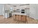 Modern kitchen with white cabinets, stainless steel appliances, island with wood base, and quartz countertops at 1279 Kindness Nw Ct, Concord, NC 28027