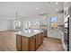 Kitchen with island, modern appliances, white cabinets and backsplash, and wood flooring at 1279 Kindness Nw Ct, Concord, NC 28027
