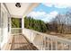 Covered porch featuring a wooden deck and railing with scenic views of the surrounding greenery at 12860 Westmoreland Farm Rd, Davidson, NC 28036
