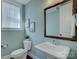 Elegant powder room with pedestal sink, decorative mirror, and soft blue walls at 1538 Riverwalk Pkwy, Rock Hill, SC 29730