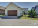 Charming home exterior featuring a dark wood garage door and a well-maintained landscaped yard and fence at 1538 Riverwalk Pkwy, Rock Hill, SC 29730