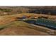 Aerial view of horse farm featuring barn, pastures, and outbuildings amid rolling hills and mature trees at 2137 Old Latter Rd, Newton, NC 28658