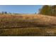 Large land plot with grassy field featuring sparse trees and shrubs against a backdrop of wooded countryside on a sunny day at 2137 Old Latter Rd, Newton, NC 28658