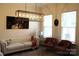 Comfortable living room featuring ample natural light, tufted sofa, modern light fixture and decorative accents at 3309 Juneberry Pl, Indian Land, SC 29707