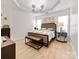 Main bedroom featuring a tray ceiling, bench at the foot of the bed, and modern light fixture at 4022 Carl Parmer Dr, Harrisburg, NC 28075